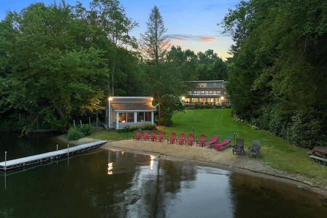 exterior space with dirt driveway, a lawn, a water view, and an outbuilding