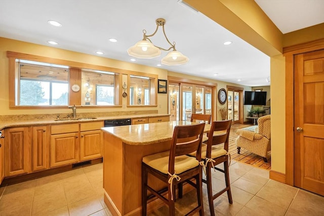 kitchen featuring light stone counters, pendant lighting, light tile patterned flooring, a sink, and a kitchen bar