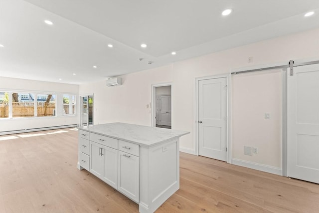kitchen with a wall unit AC, a baseboard radiator, a kitchen island, white cabinets, and light wood-type flooring