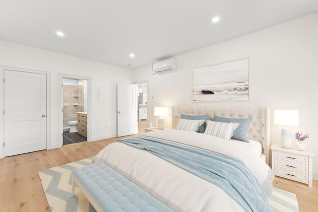 bedroom with a wall mounted AC, light wood finished floors, recessed lighting, connected bathroom, and baseboards