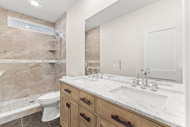 bathroom featuring a tile shower, toilet, double vanity, and tile patterned floors