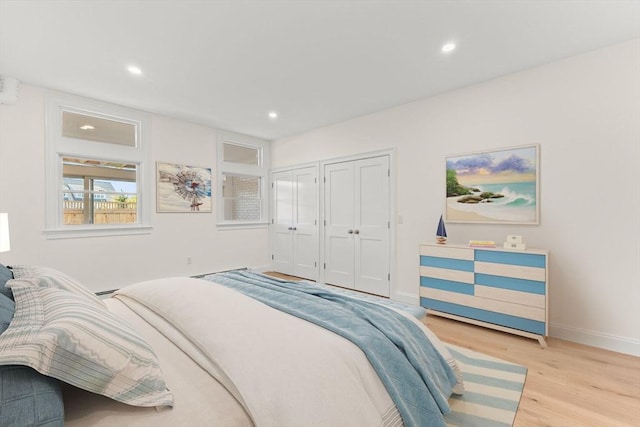 bedroom with multiple closets, light wood finished floors, recessed lighting, and baseboards