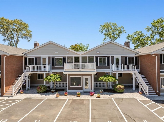 view of property featuring stairway and uncovered parking