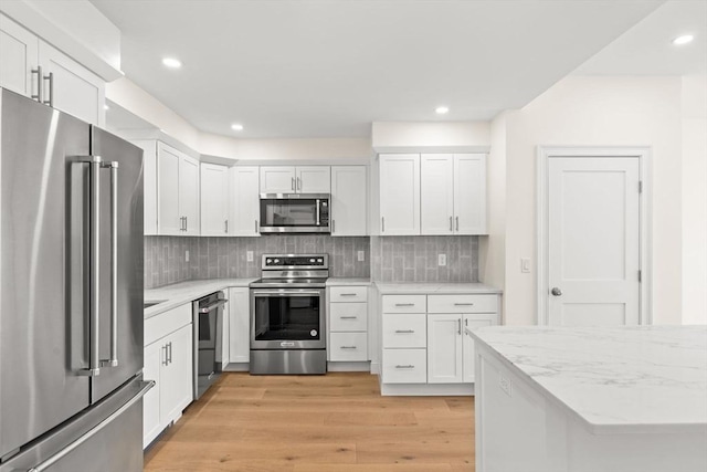 kitchen featuring appliances with stainless steel finishes, light wood-style flooring, white cabinetry, and recessed lighting