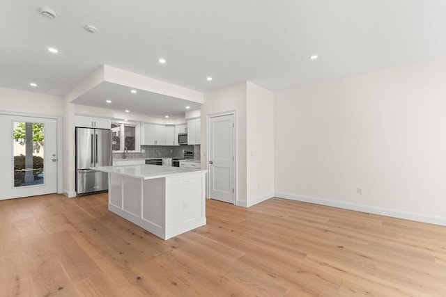 kitchen featuring stainless steel appliances, white cabinets, light wood-type flooring, a kitchen island, and recessed lighting