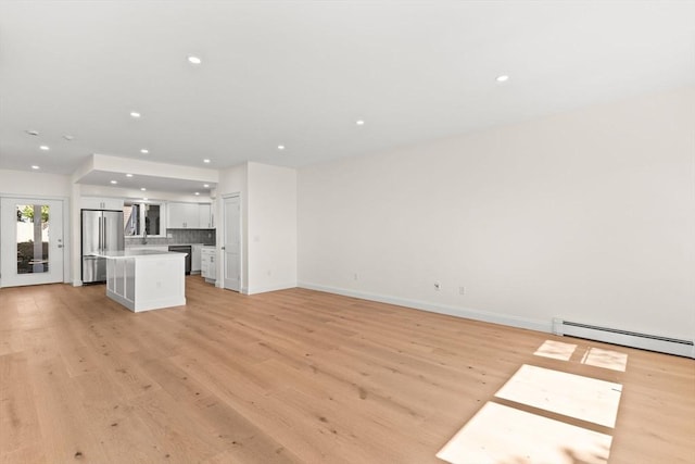 unfurnished living room featuring light wood-style floors, recessed lighting, baseboards, and baseboard heating