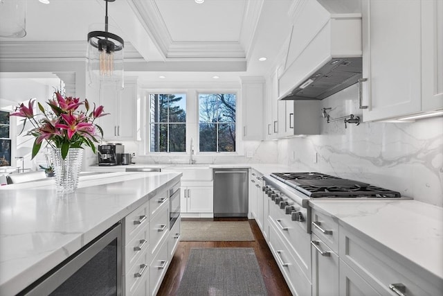 kitchen with crown molding, appliances with stainless steel finishes, white cabinets, and custom range hood