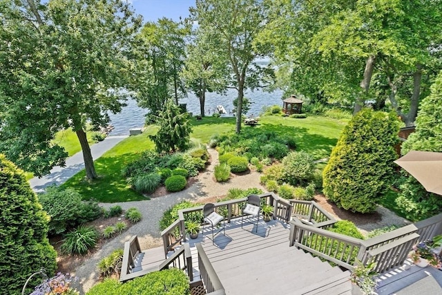 view of community with a lawn and a deck with water view