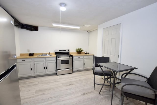 kitchen with light wood-type flooring, a sink, light countertops, stainless steel appliances, and white cabinetry
