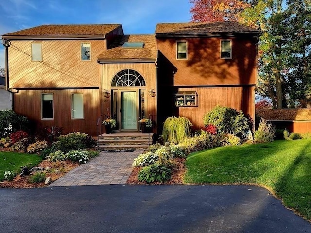 view of front of home featuring roof with shingles and a front lawn