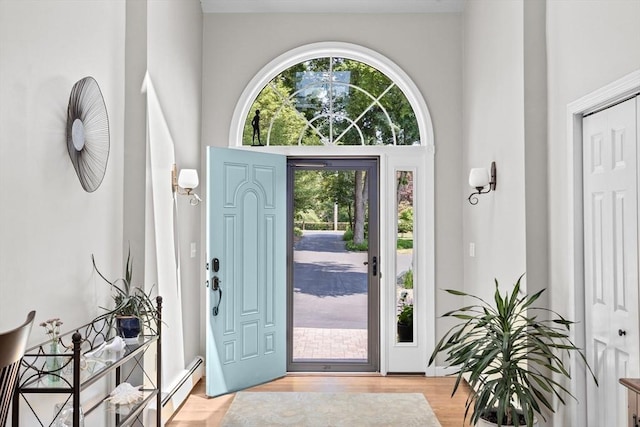 foyer entrance featuring plenty of natural light, a baseboard heating unit, and light wood finished floors
