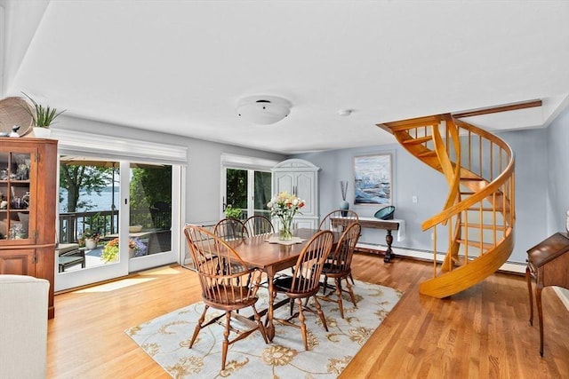 dining area with stairway, a baseboard radiator, and wood finished floors