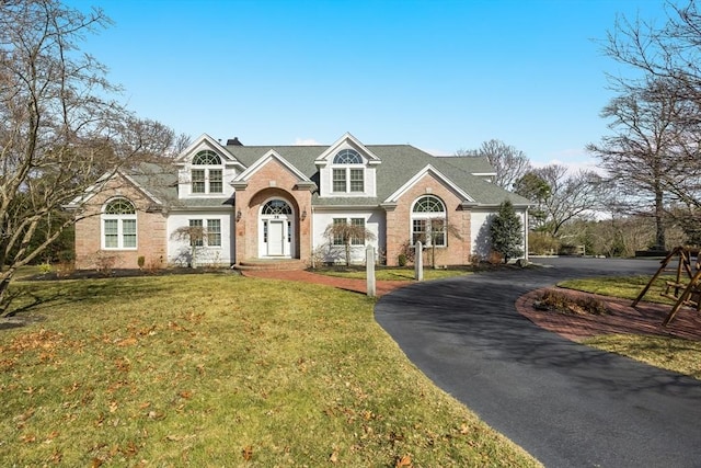 view of front facade featuring brick siding, driveway, and a front lawn