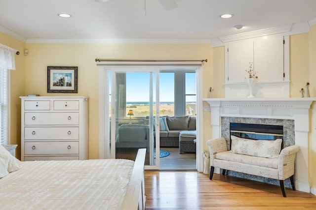 bedroom with light wood finished floors, a premium fireplace, recessed lighting, access to exterior, and crown molding