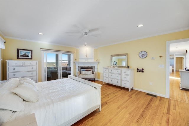 bedroom with crown molding, light wood-style flooring, a fireplace, and visible vents