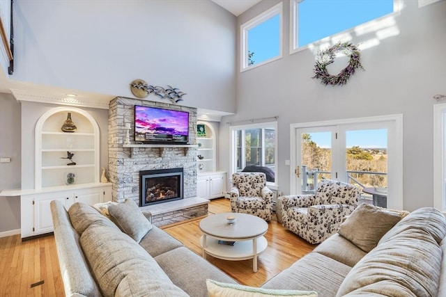 living area featuring built in features, baseboards, light wood-style flooring, and a fireplace