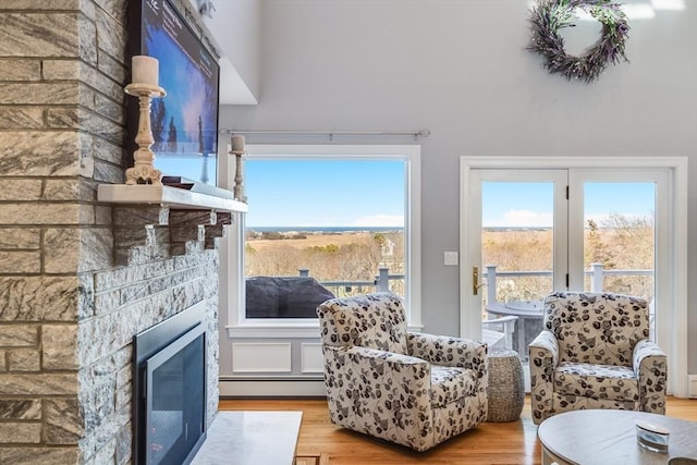 interior space featuring a glass covered fireplace, a baseboard radiator, and wood finished floors