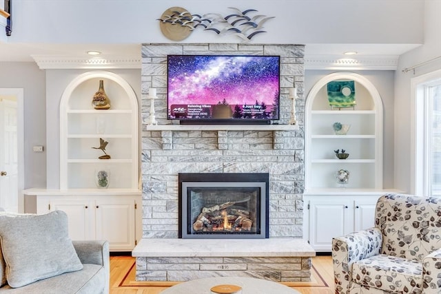 living room with a large fireplace, light wood-style floors, and built in shelves