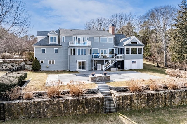 rear view of property with a patio, a balcony, stairway, a fenced backyard, and a chimney