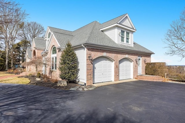 view of property exterior with aphalt driveway, brick siding, and a shingled roof