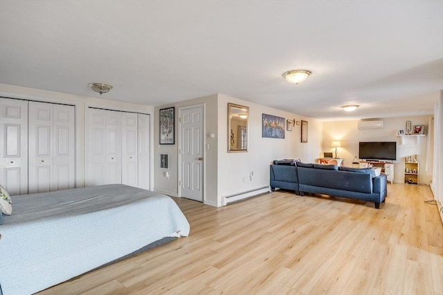 bedroom featuring a wall mounted air conditioner, a baseboard heating unit, multiple closets, and wood finished floors