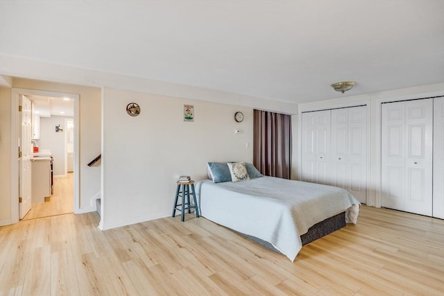 bedroom featuring baseboards, two closets, and wood finished floors