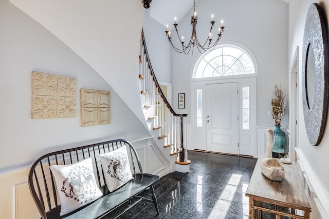 entryway featuring stairway, wainscoting, a high ceiling, granite finish floor, and a decorative wall