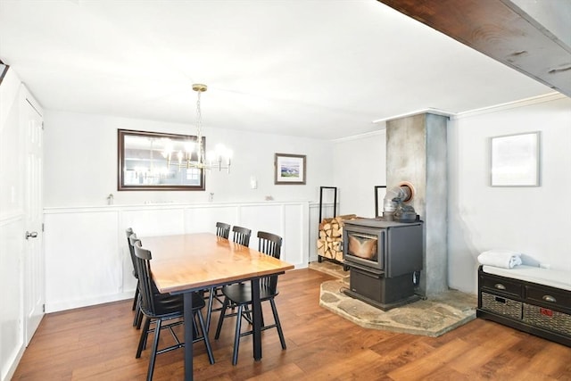 dining area featuring a wood stove, wood finished floors, and a notable chandelier