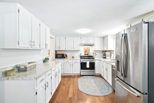 kitchen featuring under cabinet range hood, white cabinetry, appliances with stainless steel finishes, and wood finished floors