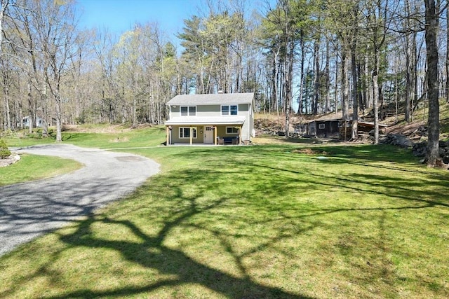 view of front facade featuring covered porch, driveway, and a front yard