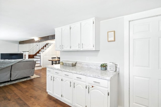 kitchen featuring light stone counters, white cabinets, dark wood finished floors, and open floor plan
