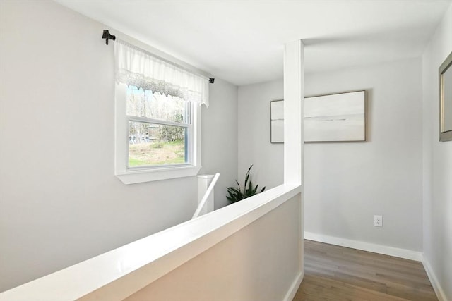 corridor with baseboards, wood finished floors, and an upstairs landing