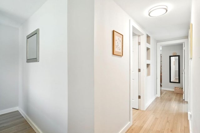corridor with baseboards and light wood-style flooring