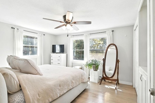 bedroom featuring baseboards, multiple windows, ceiling fan, and light wood finished floors