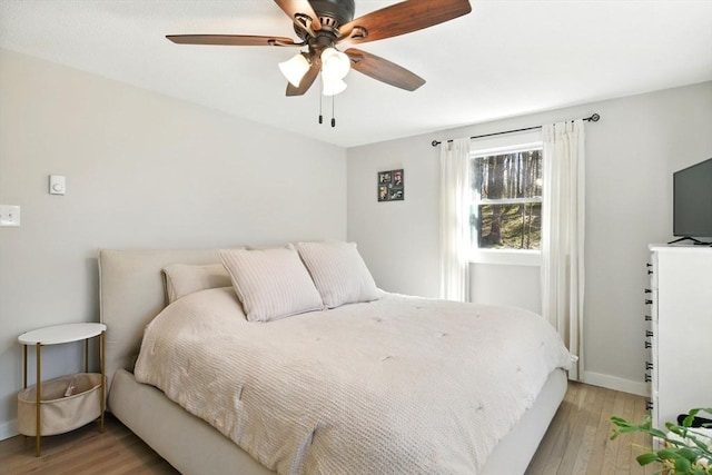 bedroom featuring baseboards, light wood-style flooring, and ceiling fan