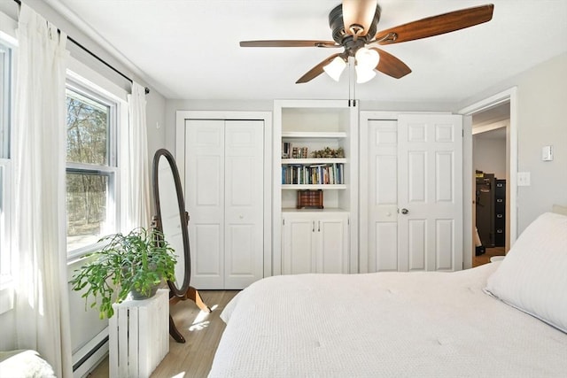bedroom featuring two closets, ceiling fan, and wood finished floors