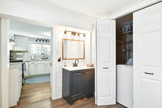 bathroom with vanity, washer / dryer, wood finished floors, ornamental molding, and a closet