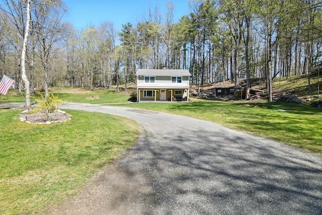 view of front of home with covered porch, curved driveway, and a front lawn