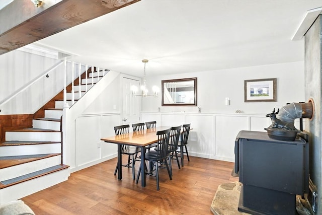 dining room with stairs, wood finished floors, a notable chandelier, and wainscoting