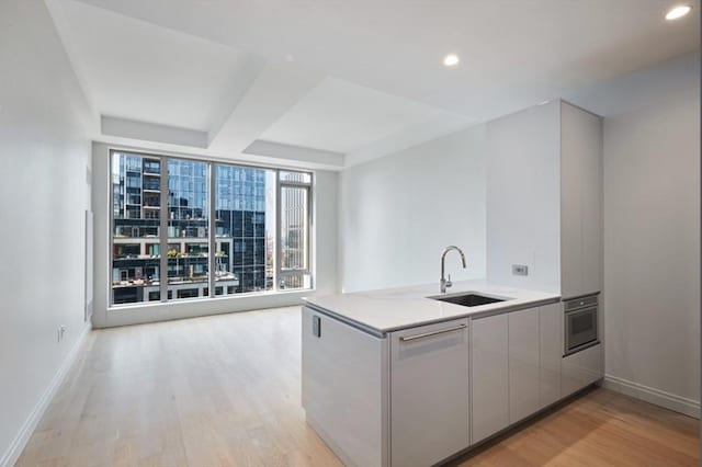 133 Seaport Blvd Unit 1007, Boston, MA 02210 - kitchen with a sink, stainless steel oven, light wood-type flooring, baseboards, and recessed lighting