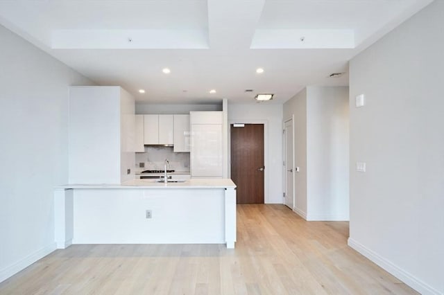 133 Seaport Blvd Unit 1007, Boston, MA 02210 - kitchen with light countertops, white cabinetry, light wood-style floors, tasteful backsplash, and baseboards