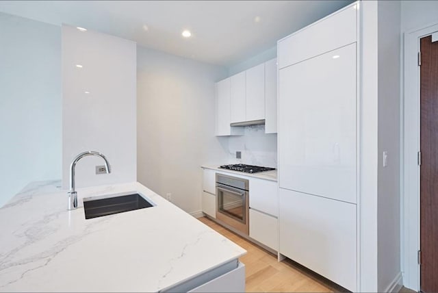 133 Seaport Blvd Unit 1007, Boston, MA 02210 - kitchen with stainless steel oven, a sink, gas cooktop, modern cabinets, and recessed lighting