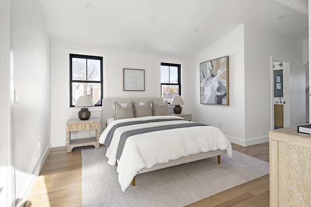 bedroom with lofted ceiling, light hardwood / wood-style floors, and ensuite bathroom