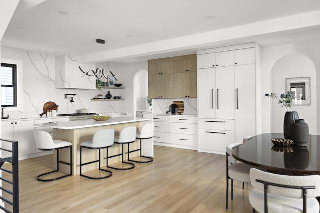 kitchen featuring backsplash, decorative light fixtures, a center island, and white cabinets