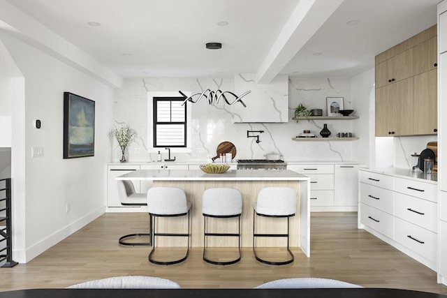 kitchen with a kitchen island, light brown cabinetry, backsplash, and a kitchen bar