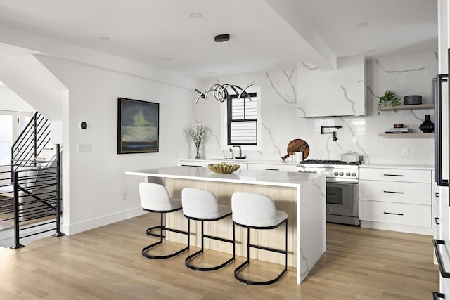 kitchen featuring light hardwood / wood-style floors, stainless steel stove, a kitchen island, and white cabinets