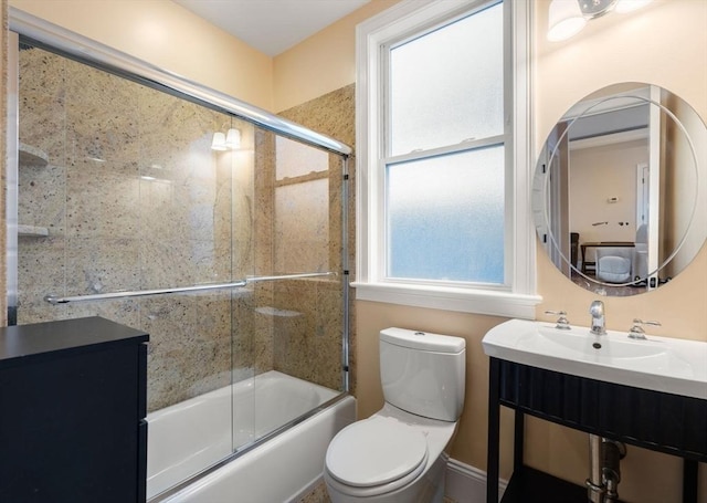 full bathroom featuring sink, bath / shower combo with glass door, and toilet