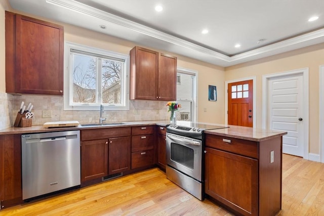 kitchen with sink, stainless steel appliances, kitchen peninsula, and light wood-type flooring