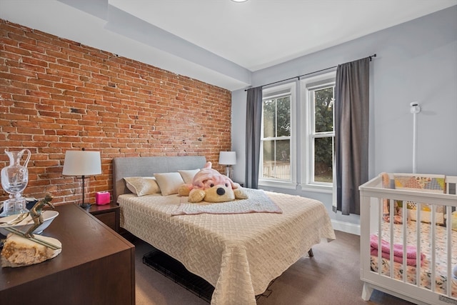 bedroom with brick wall and dark colored carpet