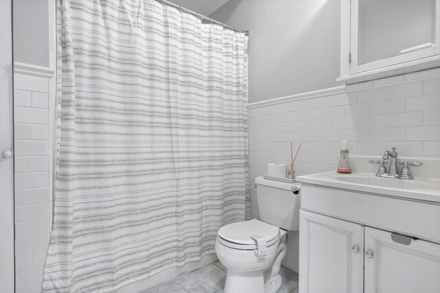 bathroom with toilet, tile patterned flooring, vanity, tile walls, and a shower with curtain